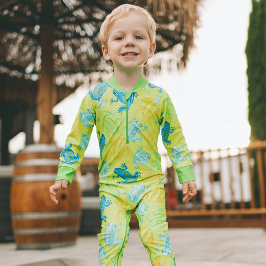 Child wearing a green and blue swimsuit with a pool in the background
