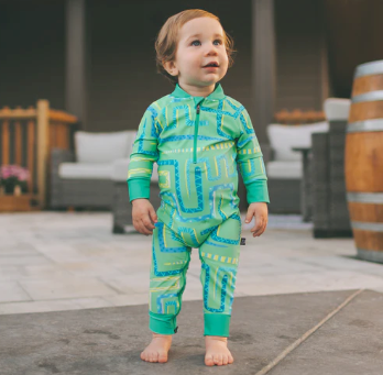 Child wearing a green and blue snake patterned outfit standing on a patio.